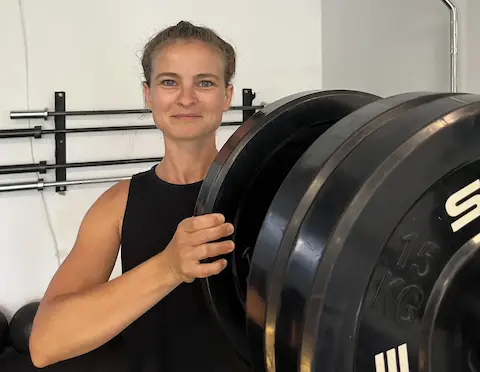 Person loading a barbell and smiling in front of the camera